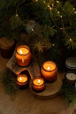 Soya mumları cam kavanozlarda yanar. Evdeki rahatlık. Kahverengi kavanozdaki mum. Koku ve ışık. Kokulu el yapımı mum. Aroma terapisi. Noel ağacı ve kış havası. Sıcak ev dekorasyonu. Şenlikli dekorasyon.