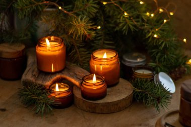 Soya mumları cam kavanozlarda yanar. Evdeki rahatlık. Kahverengi kavanozdaki mum. Koku ve ışık. Kokulu el yapımı mum. Aroma terapisi. Noel ağacı ve kış havası. Sıcak ev dekorasyonu. Şenlikli dekorasyon.