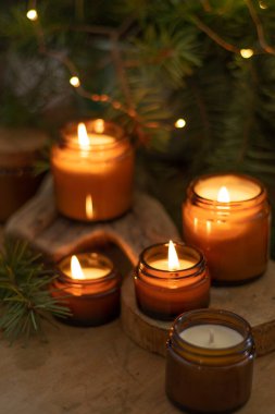 Soya mumları cam kavanozlarda yanar. Evdeki rahatlık. Kahverengi kavanozdaki mum. Koku ve ışık. Kokulu el yapımı mum. Aroma terapisi. Noel ağacı ve kış havası. Sıcak ev dekorasyonu. Şenlikli dekorasyon.