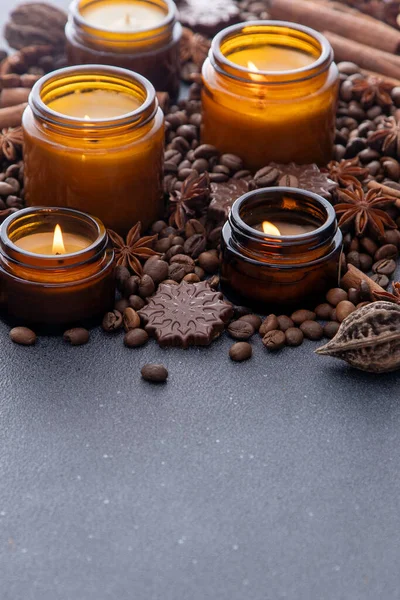Soy scented candle in a jar. Coffee beans, anise, cinnamon spices. The candles are burning. Dark copy space background.