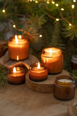 Soya mumları cam kavanozlarda yanar. Evdeki rahatlık. Kahverengi kavanozdaki mum. Koku ve ışık. Kokulu el yapımı mum. Aroma terapisi. Noel ağacı ve kış havası. Sıcak ev dekorasyonu. Şenlikli dekorasyon.