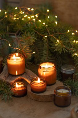 Soya mumları cam kavanozlarda yanar. Evdeki rahatlık. Kahverengi kavanozdaki mum. Koku ve ışık. Kokulu el yapımı mum. Aroma terapisi. Noel ağacı ve kış havası. Sıcak ev dekorasyonu. Şenlikli dekorasyon.