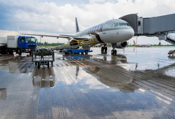 Yağmurlu bir hava. Yolcular biniyor, bagaj yükleniyor. Havaalanı pistindeki Katar Havayolları uçağı. Airbus A320-232, uçak A7-AHR. Ukrayna, Kyiv, - 28 Mayıs, 2021