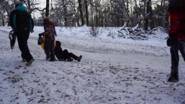 Ukrayna, Kyiv - 15 Ocak 2021: İnsanlar kar tepesinde kayıyor. Kışın karlı bir günde plastik bir kızakla kayan çocuklar. Mutlu bir çocukluk. Dışarıda kar yağıyor. Tatil eğlencesi Park Dubki