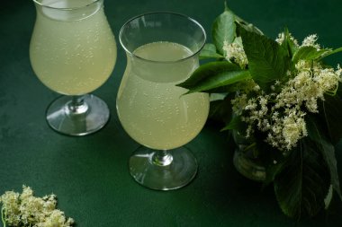 Karbonatlı mürver çiçeği içeceği. Gözlüklü yaz kvass 'ı. Ev yapımı köpüklü hugo suyu. Yeşil arkaplan