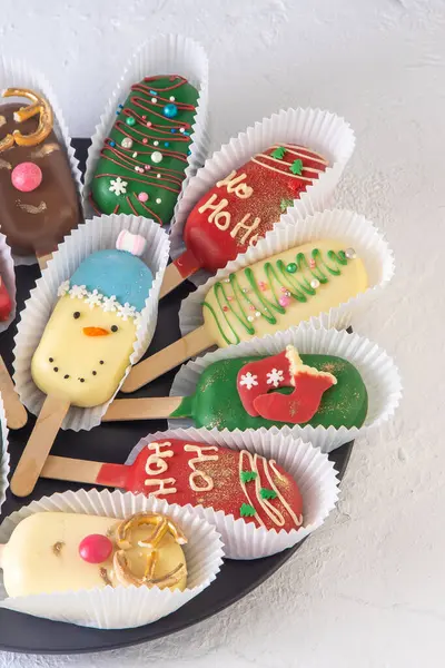 stock image Christmas dessert. Sweet food. Cheesecake on a stick in the shape of ice cream. Childrens treat in winter. Candy Christmas tree, snowman, deer and Santa Claus. Gingerbread cookies. White background.