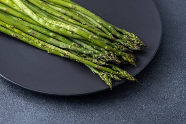 Bir sürü yeşil kuşkonmaz. Taze bahar sebzeleri ızgarada. Siyah tabak..