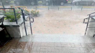 Yağmur, gök gürültüsü ve dolu evin verandasında. Güçlü fırtına kasırgası. Şehir kafesinde kötü yağmur havası var.