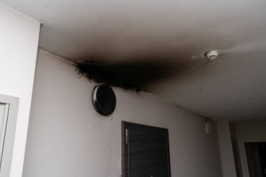 Yanmış LED lamba. Yangından sonra duvarda bir abajur lambası. Konut binasında kendiliğinden yanma ve yangın. Yangın alarmı algılayıcısı içeride