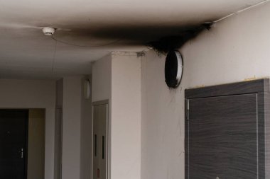 Yanmış LED lamba. Yangından sonra duvarda bir abajur lambası. Konut binasında kendiliğinden yanma ve yangın. Yangın alarmı algılayıcısı içeride. Kapı