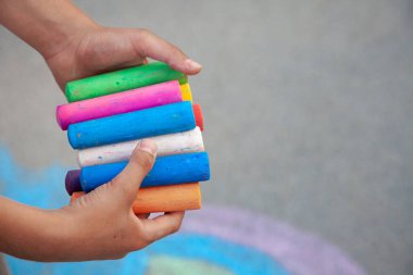 Tebeşir çubukları. Çocukların ellerinde büyük renkli kaldırım boyaları vardı. Tebeşiri çocuk tutuyor. Okula geri dön kopyalama alanı