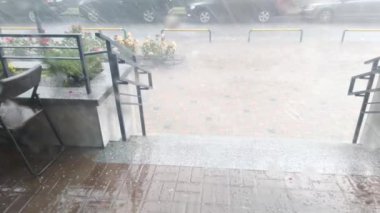 Yağmur, gök gürültüsü ve dolu evin verandasında. Güçlü fırtına kasırgası. Şehirde kötü hava var. Kasırga