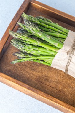 Bunch of green asparagus. Fresh spring vegetable in wooden tray