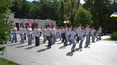 Ukraynalı çocuklar ve gençler savaş sırasında sokaklarda dans ediyorlar. Beyaz tişörtlü kızlar ve oğlanlar. Ukrayna bayrağı. Bağımsızlık ve Zafer Günü. Ukrayna, Truskavets - 7 Ağustos 2024