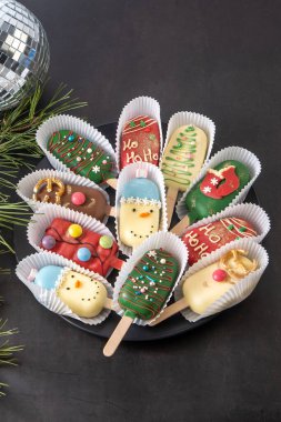 Christmas dessert. Sweet food. Cheesecake on a stick in the shape of ice cream. Kids treat in winter. Candy Christmas tree, snowman, deer and Santa Claus. Gingerbread cookies. clipart