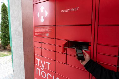 Receiver mail at the NOVA POSHTA parcel terminal. Contactless sending delivery of correspondence. Ukraine, Kyiv - March 23, 2024 clipart