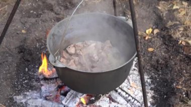 Kazanda ateşte yahni pişirilmiş et. Kaynatma ve kızartma. Kamp ateşi, açık hava yemekleri.