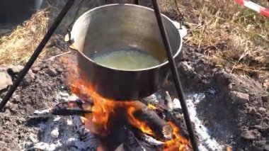 Yangında kazan var. Yürüyüşte yemek pişirmek. Kamp alanında yemek çorbası. Aşırı seyahat turizmi. Soğan karışımını kızart.
