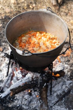 Et, soğan ve havuç bir ateşin üzerinde bir kazanda pişirilir. Sebze yahnisi. Kaynatma ve kızartma. Kamp ateşi aşçısı. Kamp yemeği hazırlayın.