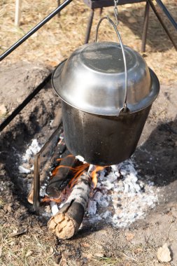 Kapaklı kamp tenceresi. Yürüyüşte kamp ateşinde yemek pişirmek. Ateş kömürü. Caldron gerçekçiliği dışarıda pişiyor. Yakacak odun yanığı. Açık havada yaz