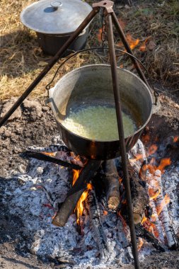Yürüyüş yaparken kamp ateşinde sebze pişir. Borş için kızarmış soğan. Dışarıdaki bir kazanda çorba içmek. Kamp ve turizm. Doğada odun ateşi