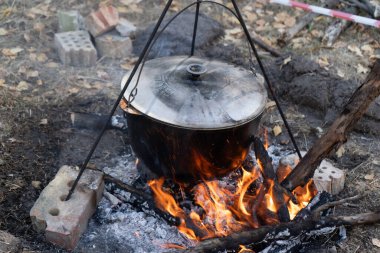Kazanda, ateş tripodunun üzerinde et çorbası. Kamp ateşi aşçısı. Yakacak odun kömürleri. Kamp ateşi yemeği. Turist yürüyüşü.