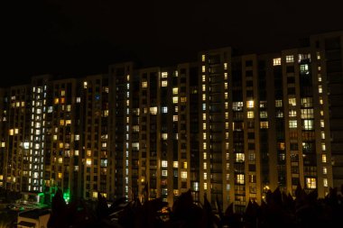 Gece büyük şehir ışığı. Çok katlı bir bina. Evin pencereleri karanlıkta parıldıyor. Modern mimari. Apartman