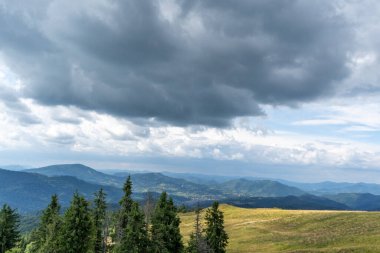 Kara yağmurlu bulutlar. Dağların üzerindeki mavi gökyüzü. Karpatlar 'daki Yeşil Orman Doğa Ağaçları.