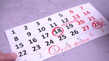 Bir iş haftası planlayın. Takvim tarihlerinde daire çiz ve vur. Kırmızı kalemle yaz. El planlama tarihleri. Ziyaretçi doktor.