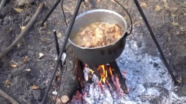 Kazanda ateşte pişmiş et var. Kaynatma ve kızartma. Kamp ateşi, açık hava yemekleri aşçısı.