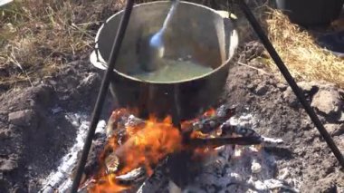 Yangında kazan var. Yürüyüşte yemek pişirmek. Kamp alanında yemek çorbası. Aşırı seyahat turizmi. Kaşığı kızart soğanı