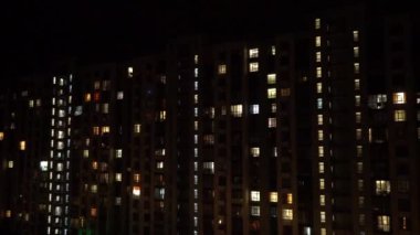 Gece büyük şehir ışığı. Çok katlı bir bina. Evin pencereleri karanlıkta parıldıyor. Modern mimari
