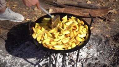 Kamp ateşinde yürüyüş yaparken yemek pişirmek. Yağda kızartılmış patates. Dışarıdaki yangında kızartma tavası. Doğada yemek pişirmek. El karışımı