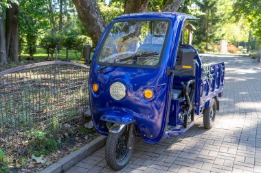 Kulübeli üç tekerlekli motosiklet. Bir kişilik römorklu mavi küçük bir araba. Akıllı taşıma. Elektrikli kargo üç tekerlekli bisiklet.