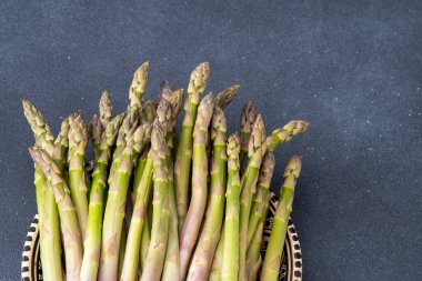 Koyu arkaplanda yeşil kuşkonmaz. Sebze filizleri. Taze yemek kasesi üst görünümü.