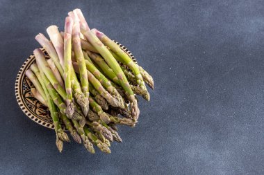 Koyu arkaplanda yeşil kuşkonmaz. Sebze filizleri. Taze yemek kasesi manzarası. Boşluğu kopyala.