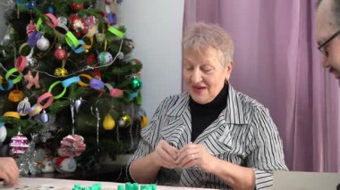 Yaşlı bir emekli kadın bingo oynuyor. Ailesiyle birlikte bir büyükanne evdeki Noel ağacının altında masa oyunu oynuyor. Piyango