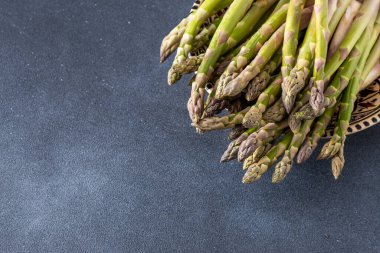 Koyu arkaplanda yeşil kuşkonmaz. Sebze filizleri. Taze yemek kasesi manzarası. Boşluğu kopyala.