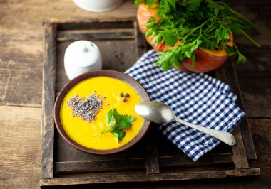 Bir kase kremalı balkabağı havuç çorbası ve garnitür.