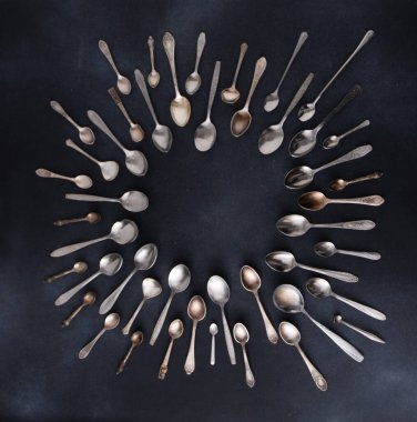 Farklı eski kaşıklar. Siyah arka planda gümüş çatal bıçak seti. Kaşığı masaya koy. Çember çerçeve üst görünüm kopyalama alanı