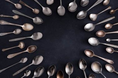 Farklı kaşıklar. Siyah arka planda gümüş çatal bıçak seti. Kaşığı masaya koy. Çember çerçeve üst görünümü kopyala mutfak gereçleri