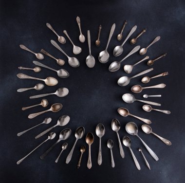 Farklı kaşıklar. Siyah arka planda gümüş çatal bıçak seti. Kaşığı masaya koy. Çember çerçeve üst görünüm kopyalama alanı. Çatal bıçak takımı