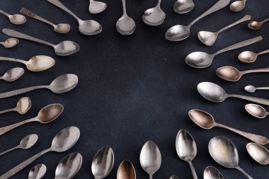 Farklı kaşıklar. Siyah arka planda gümüş çatal bıçak seti. Kaşığı masaya koy. Çember çerçeve üst görünüm kopyalama alanı çatal bıçak takımı