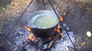 Yangında kazan var. Yürüyüşte yemek pişirmek. Kamp alanında yemek çorbası. Seyahat turizmi aşırı yürüyüş aşçılığı