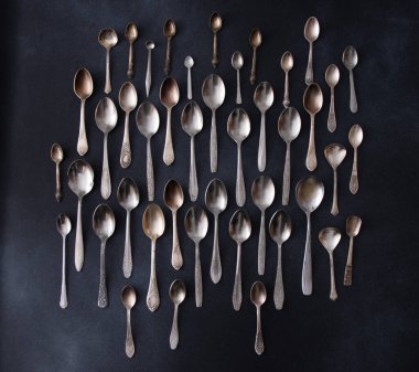 Farklı kaşıklar. Siyah arka planda gümüş çatal bıçak seti. Kaşığı masaya koy. Kullanıcı paslanmaz