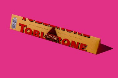 Toblerone marka çikolata ambalajı. İsviçre Mondelez şekeri. Pembe arka planda sarı paket. Ukrayna, Kyiv - 4 Kasım 2024.