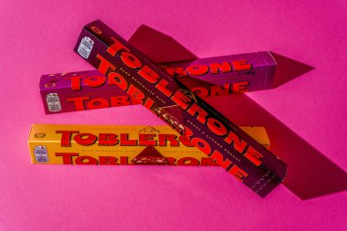 Toblerone marka çikolata ambalajı. İsviçre Mondelez şekeri. Pembe arka planda üç paket üst görünüm. Ukrayna, Kyiv - 4 Kasım 2024.