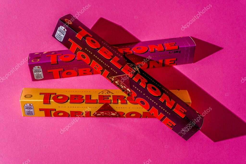 Toblerone brand chocolate packaging. Swiss Mondelez candy. Three packs top view on pink background. Ukraine, Kyiv - November 4, 2024.