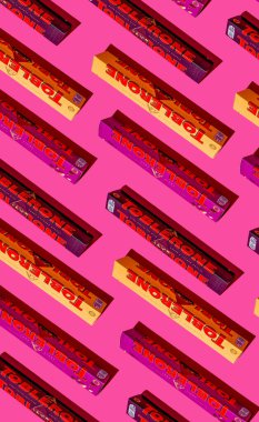 Toblerone marka çikolata. İsviçre Mondelez şekeri. Pembe arkaplan desenli farklı aromalı paketler. Ukrayna, Kyiv - 4 Kasım 2024.