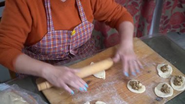 Kadınların elleri hamuru tahta bir oklavayla çevirir. Etli turta yapıyorum. Büyükanne yemek pişiriyor.